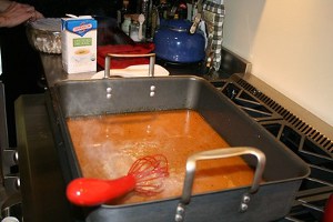 A large oven tray filled with steaming hot gravy